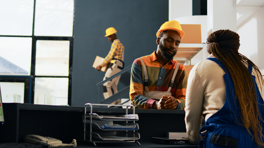 Workers talking about order management at depot, planning manufacturing and stock shipment for retail store production. Storehouse employees moving merchandise goods. Handheld shot.